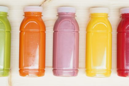 eine Reihe wiederverwendbare Flaschen aus Bio-Kunststoff gefüllt mit verschiedenfärbigen Säften